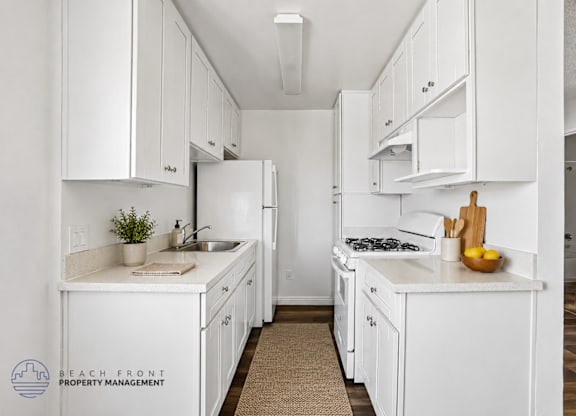 A kitchen with white cabinets and appliances, a sink, and a cutting board with lemons on the counter.