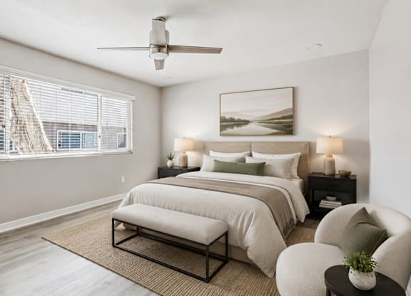 A bedroom with a large bed, a ceiling fan, and a window with blinds.