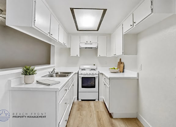 A kitchen with white cabinets and a stove top oven.