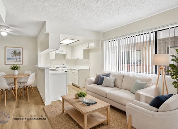 A well-lit, modern living room with a dining area and kitchen in the background.