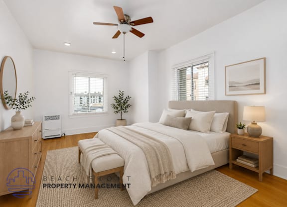 A well-lit bedroom with a large bed and a ceiling fan.
