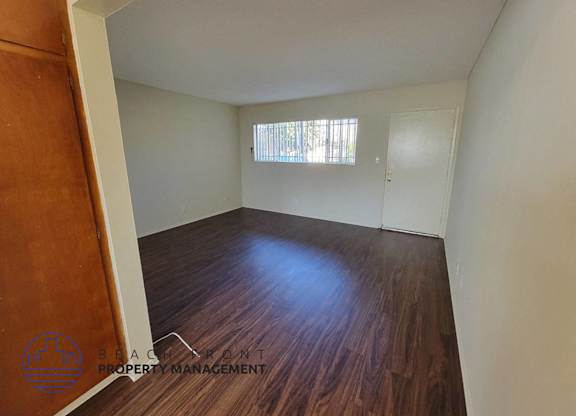 the living room of a house with wood flooring and a window