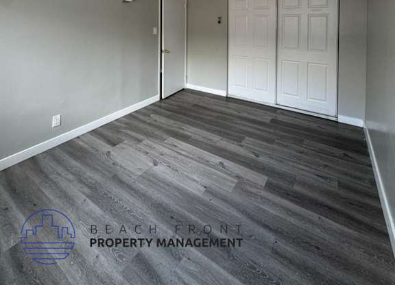 an empty living room with a white door and wood floors