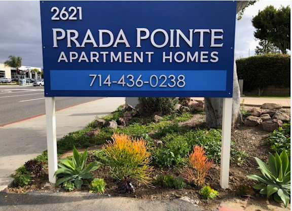 A blue sign for Prada Pointe Apartment Homes with a phone number on it.