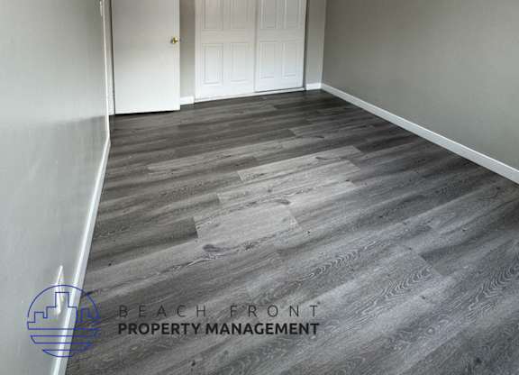 a empty room with a white door and wood flooring