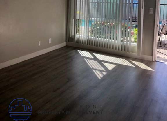 A room with a sliding glass door and wooden flooring.