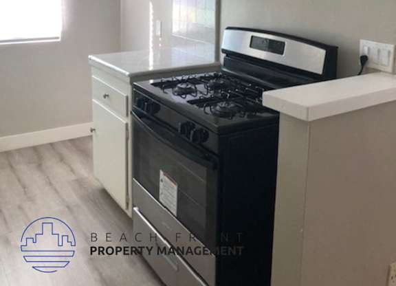 A kitchen with a black stove top oven and white cabinets.