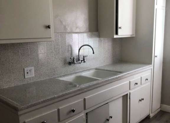 A kitchen with white cabinets and a granite countertop.