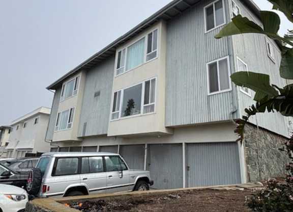 A grey building with a white car parked in front.