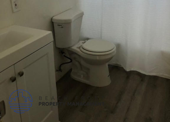 A white toilet sits next to a white sink in a small bathroom.