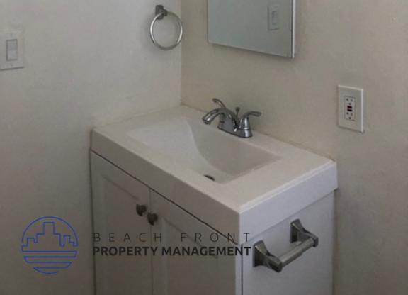 A bathroom with a sink, mirror and a logo for Beach Front Property Management.
