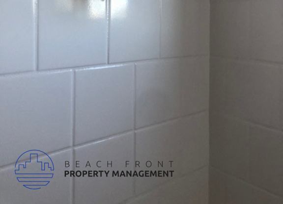 A shower head mounted on a white tiled wall.