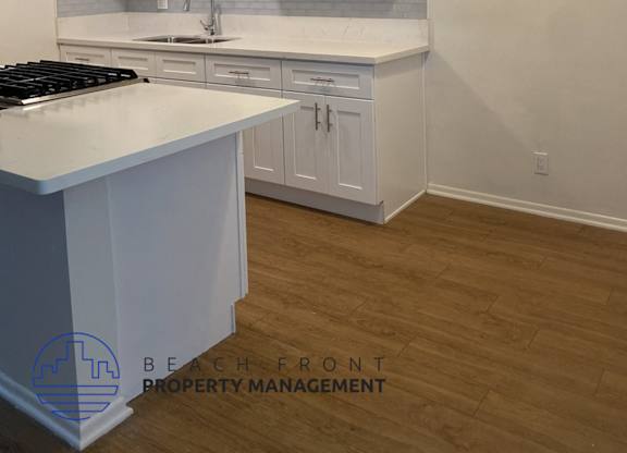 A kitchen with white cabinets and a white countertop.