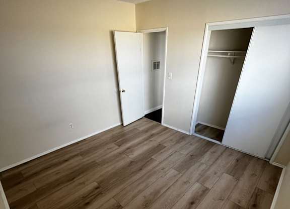 A room with wooden flooring and two open doors.