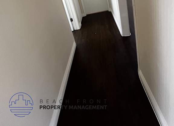 A hallway with white walls and a wooden floor.