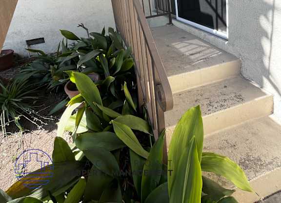 A balcony with a railing and steps leading up to a glass door.
