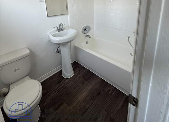 A white bathroom with a toilet, sink, and bathtub.