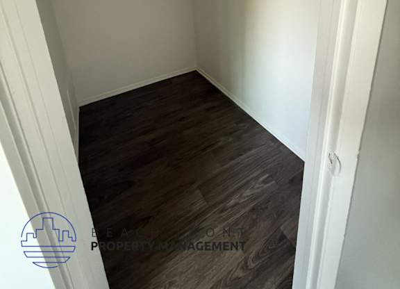 A small, empty room with wooden flooring and white walls.