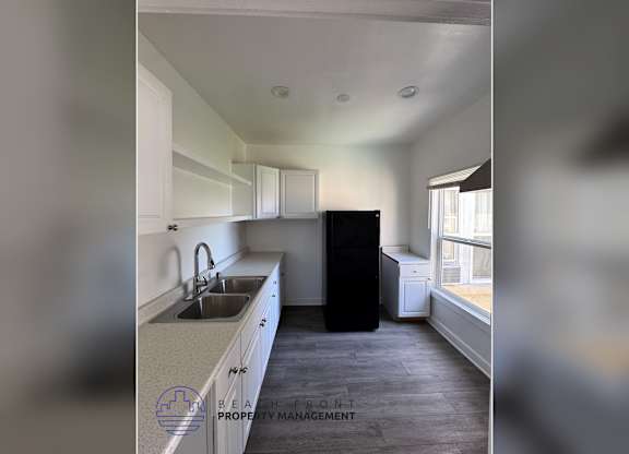 A kitchen with a sink, a window, and a refrigerator.
