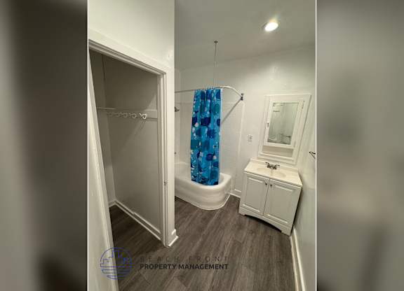A bathroom with a white cabinet, a blue shower curtain, and a white toilet.