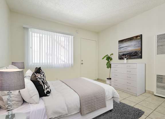 A bedroom with a bed, nightstand, and a painting on the wall.