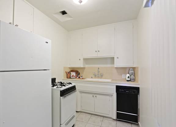 A white kitchen with a refrigerator, stove, and oven.