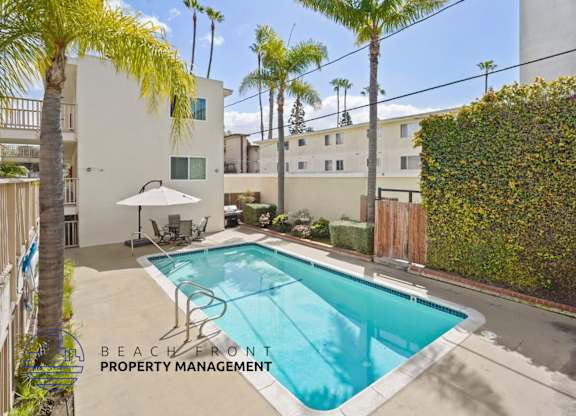 A pool surrounded by a patio and palm trees.