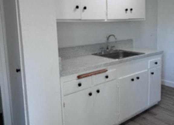 A kitchen with white cabinets and a sink.