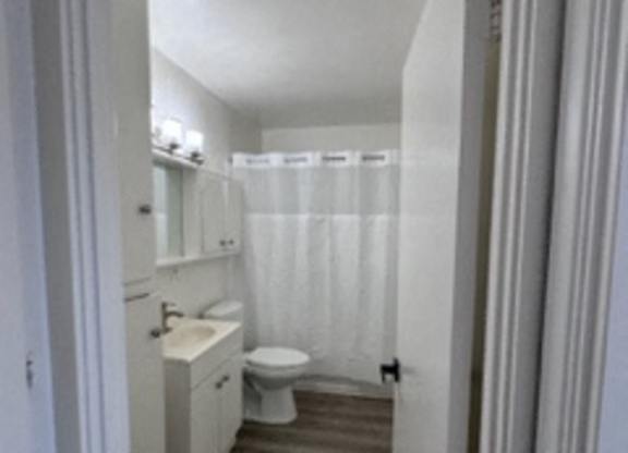 A white bathroom with a toilet, sink and shower.