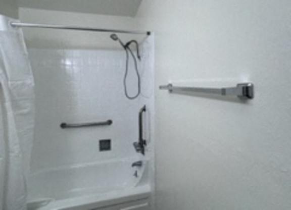A white bathroom with a toilet, shower and a towel rack.