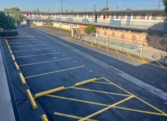 A parking lot with yellow lines and a pool in the background.