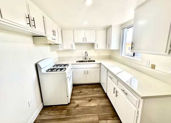 an empty kitchen with white cabinets and a window