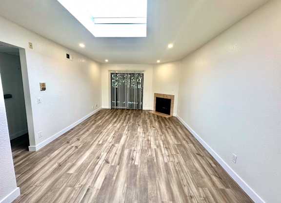 the living room of a new home with wood flooring and a fireplace