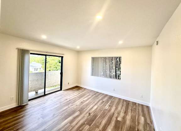 an empty living room with a sliding glass door to a patio