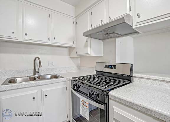 A modern kitchen with a stove top oven and a sink.