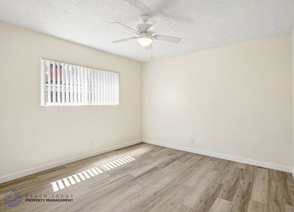 A room with a ceiling fan and a window with blinds.
