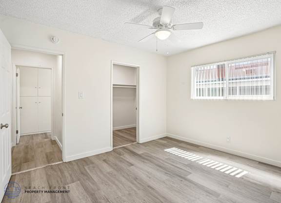 A room with a ceiling fan and a window with blinds.