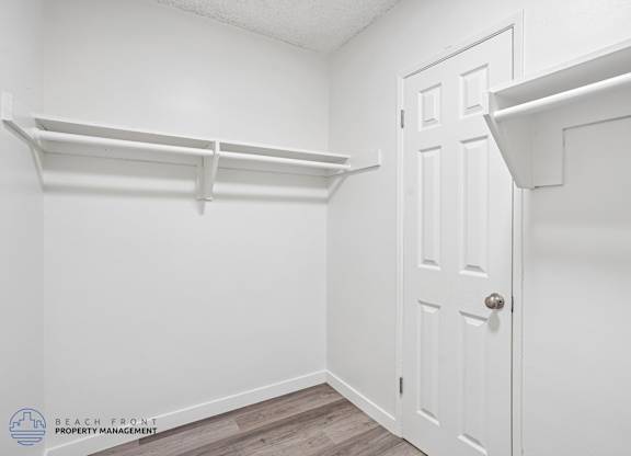 A white door is in a white room with a white shelf above it.