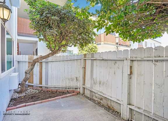 A tree in a yard with a white fence.