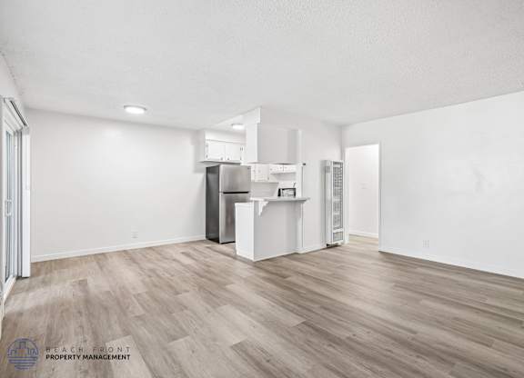 A spacious kitchen with white cabinets and a wooden floor.