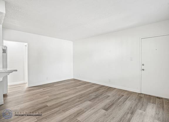 A room with wooden flooring and white walls, with a door on the right side.