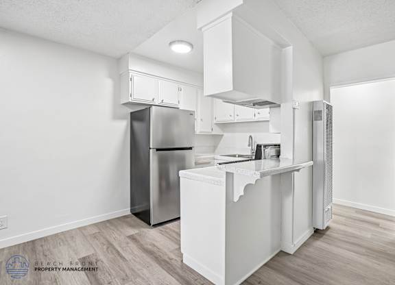 A kitchen with white cabinets and a stainless steel refrigerator.
