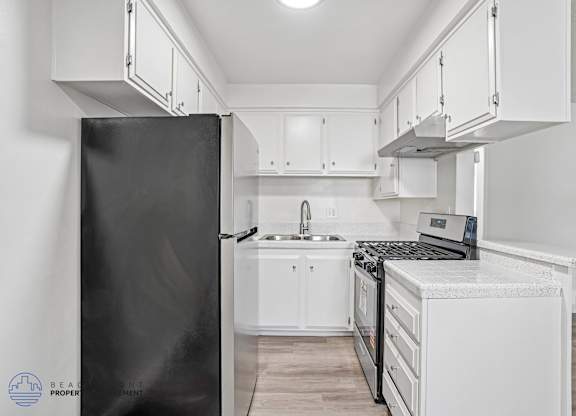 A kitchen with a black refrigerator and white cabinets.