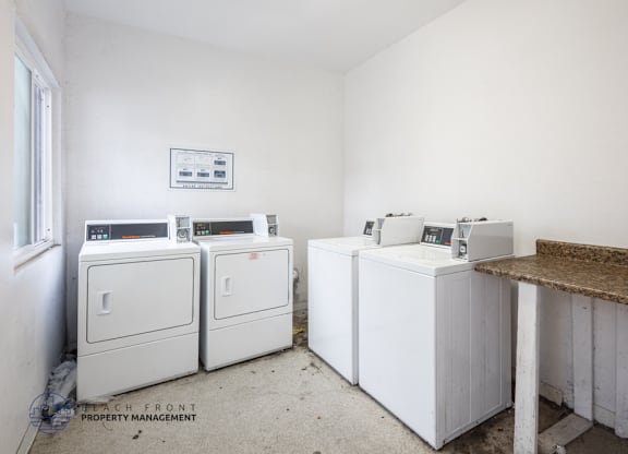 A white room with a brown counter and a fridge on the left.