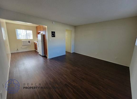 the living room and kitchen of an empty apartment with wood flooring