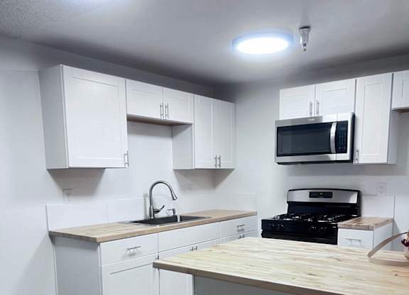 A kitchen with white cabinets and a wooden counter.