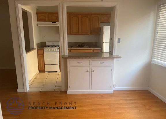 an empty kitchen with wooden floors and white cabinets