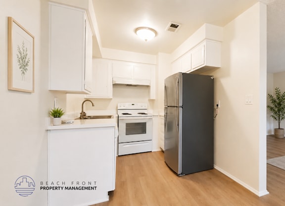 A modern kitchen with a refrigerator, sink, and cabinets.