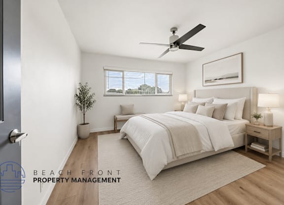 A well-lit bedroom with a large bed and a ceiling fan.