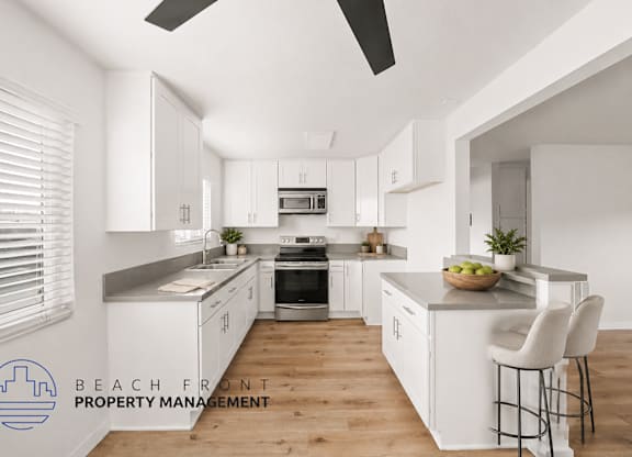 A modern kitchen with white cabinets and a wooden floor.